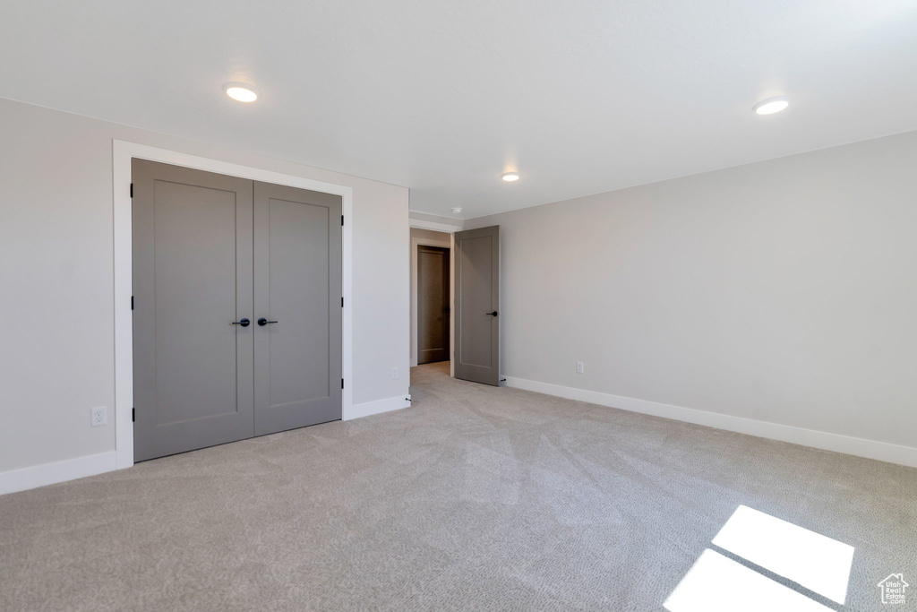 Unfurnished bedroom with light colored carpet and a closet