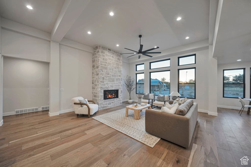 Living room featuring ceiling fan, light hardwood / wood-style floors, and a stone fireplace