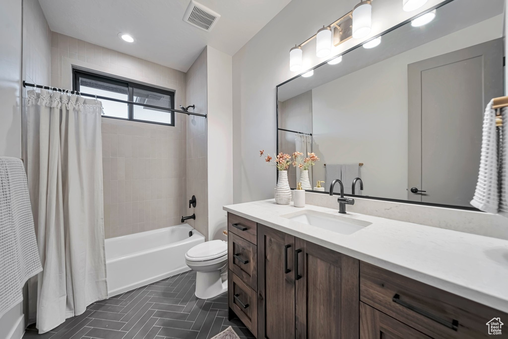 Full bathroom featuring shower / bath combination with curtain, vanity, and toilet