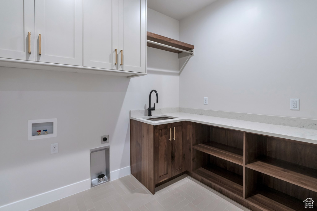 Washroom featuring hookup for a washing machine, cabinets, light tile patterned floors, sink, and electric dryer hookup