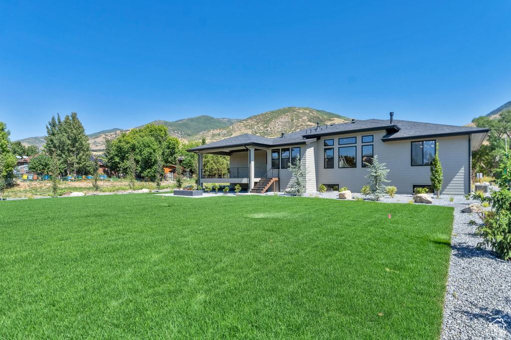 Back of property featuring a mountain view and a yard