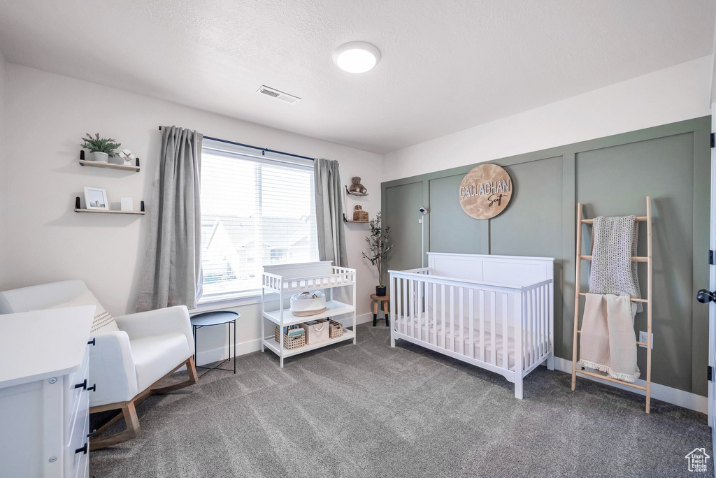 Carpeted bedroom featuring a crib