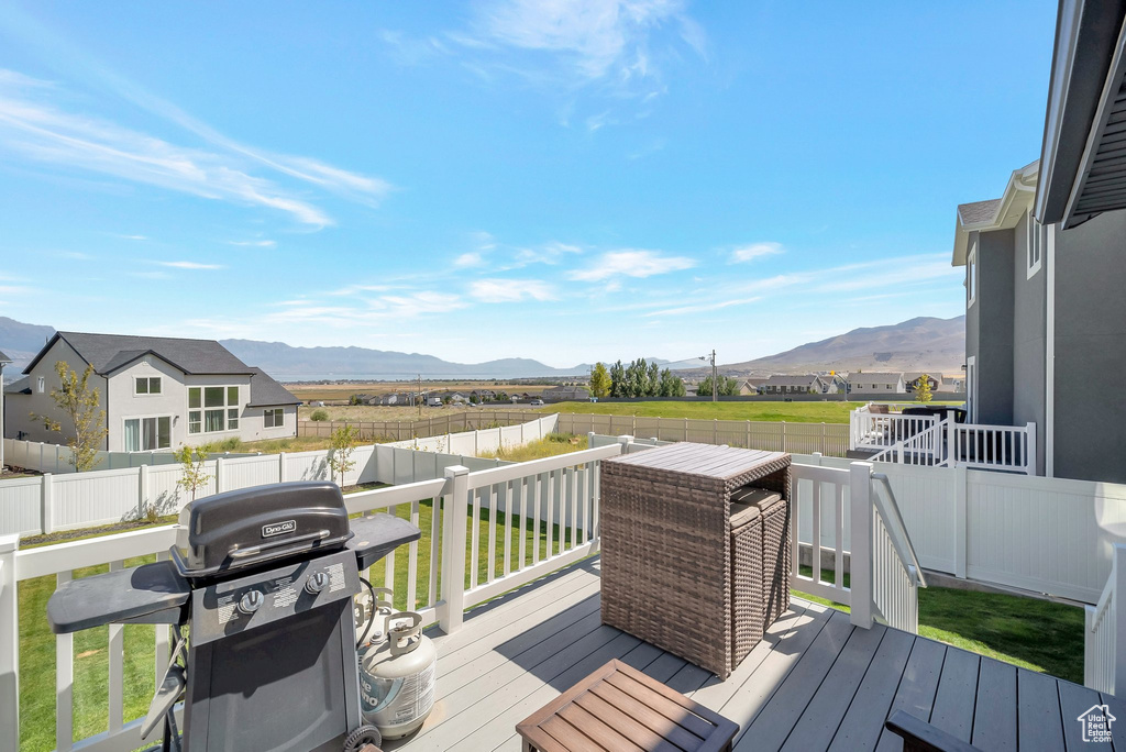 Wooden terrace with a grill, a lawn, and a mountain view