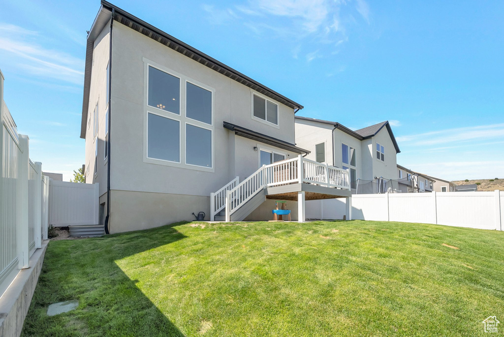 Back of property featuring a yard and a wooden deck