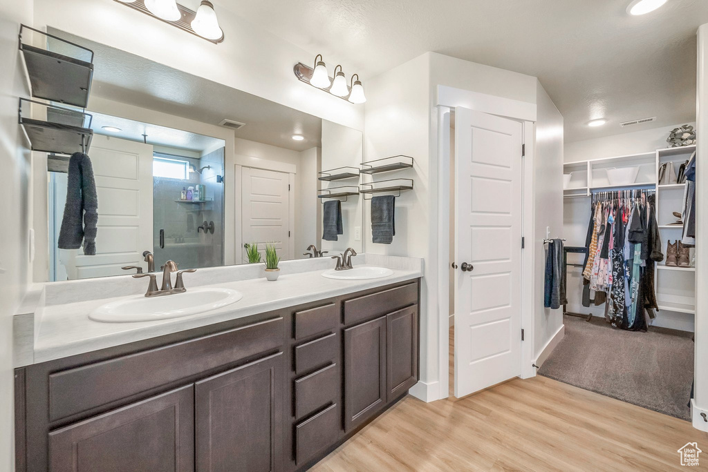 Bathroom with a shower with door, vanity, and hardwood / wood-style floors