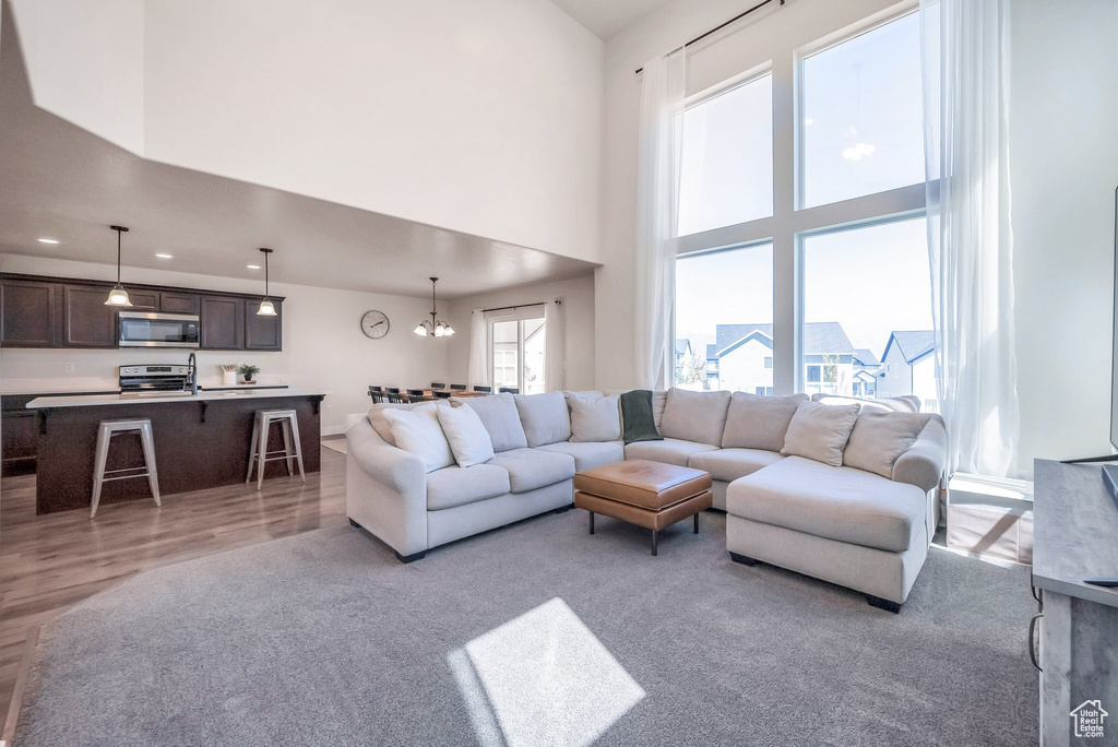 Living room featuring a high ceiling, a chandelier, and light hardwood / wood-style flooring