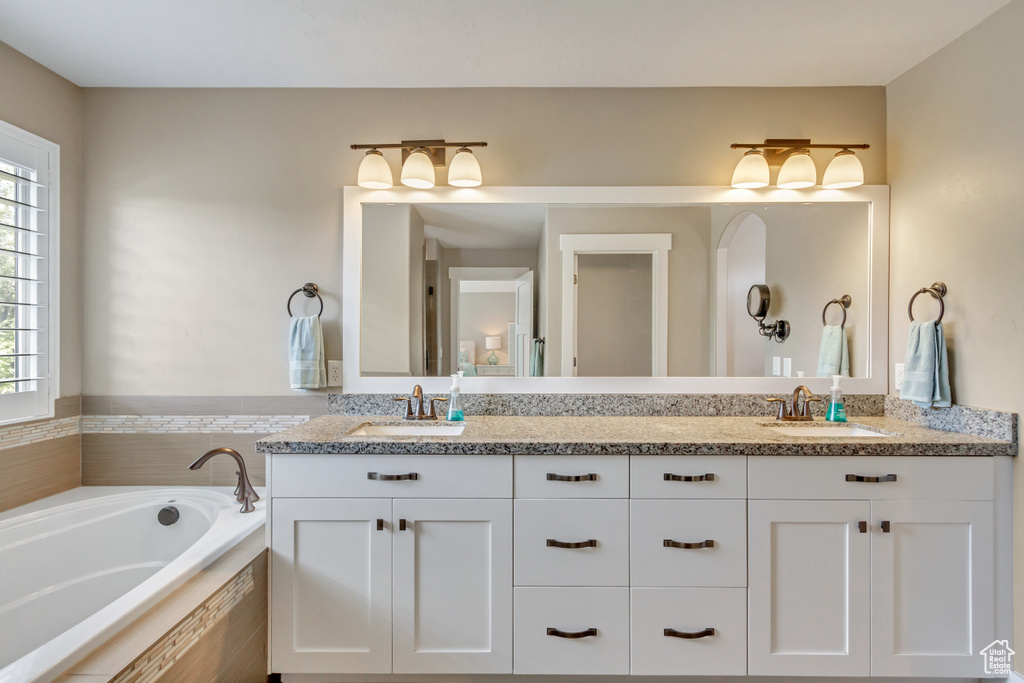 Bathroom featuring vanity, plenty of natural light, and a relaxing tiled tub