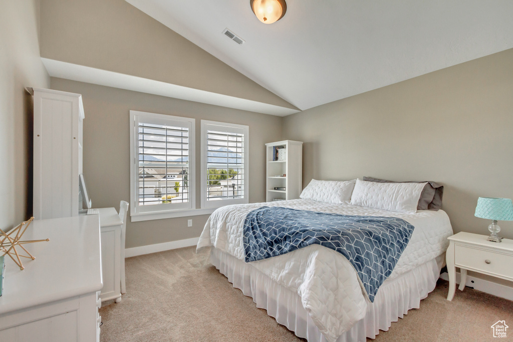 Bedroom featuring light colored carpet and vaulted ceiling