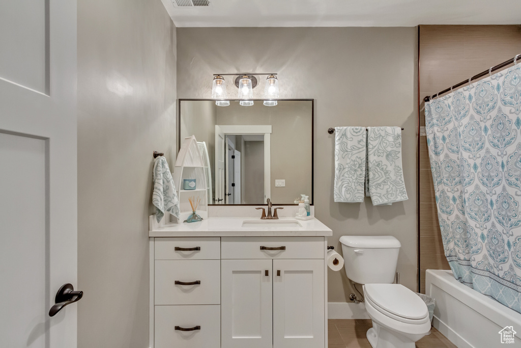 Full bathroom featuring tile patterned flooring, toilet, shower / tub combo, and vanity