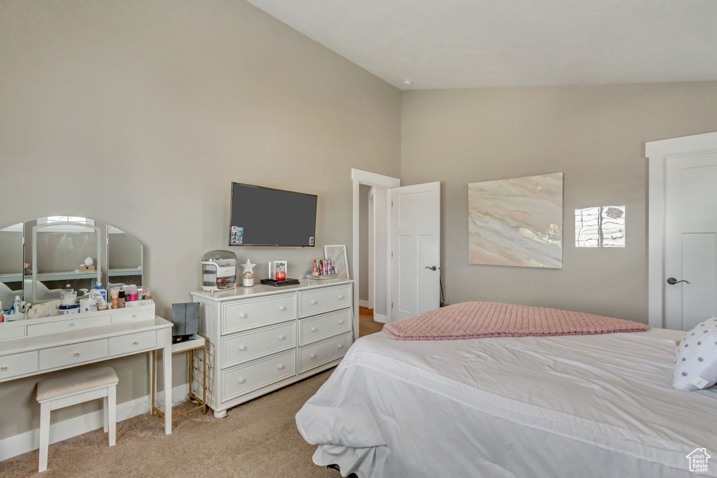 Bedroom featuring light carpet and high vaulted ceiling