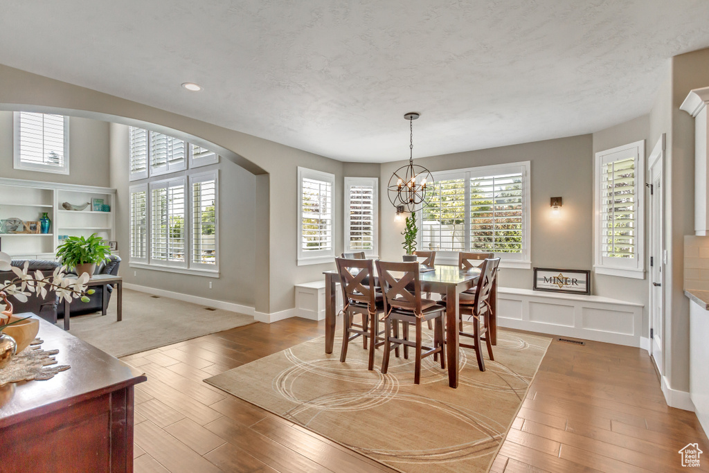 Dining room featuring a wealth of natural light, a notable chandelier, a textured ceiling, and light hardwood / wood-style floors