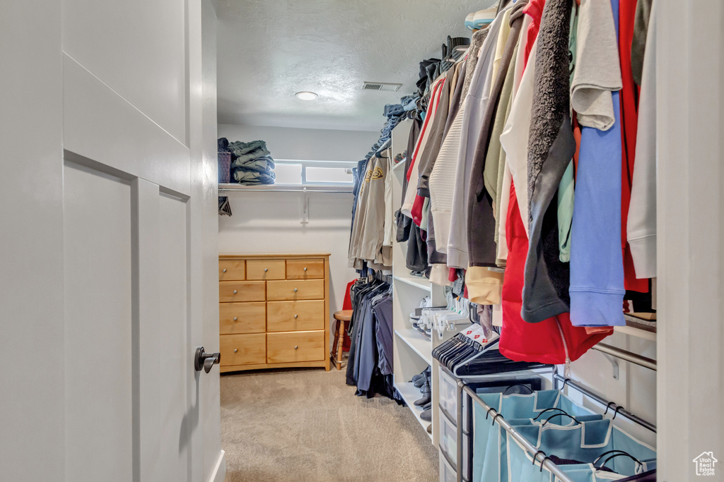 Walk in closet featuring light colored carpet