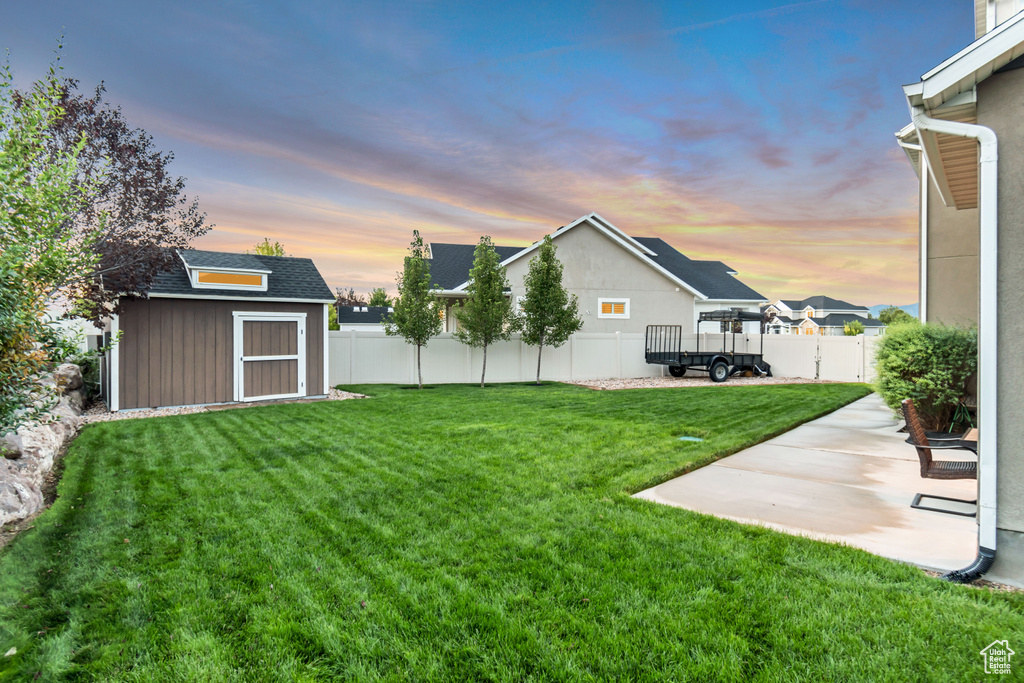 Yard at dusk with a patio area and a storage unit