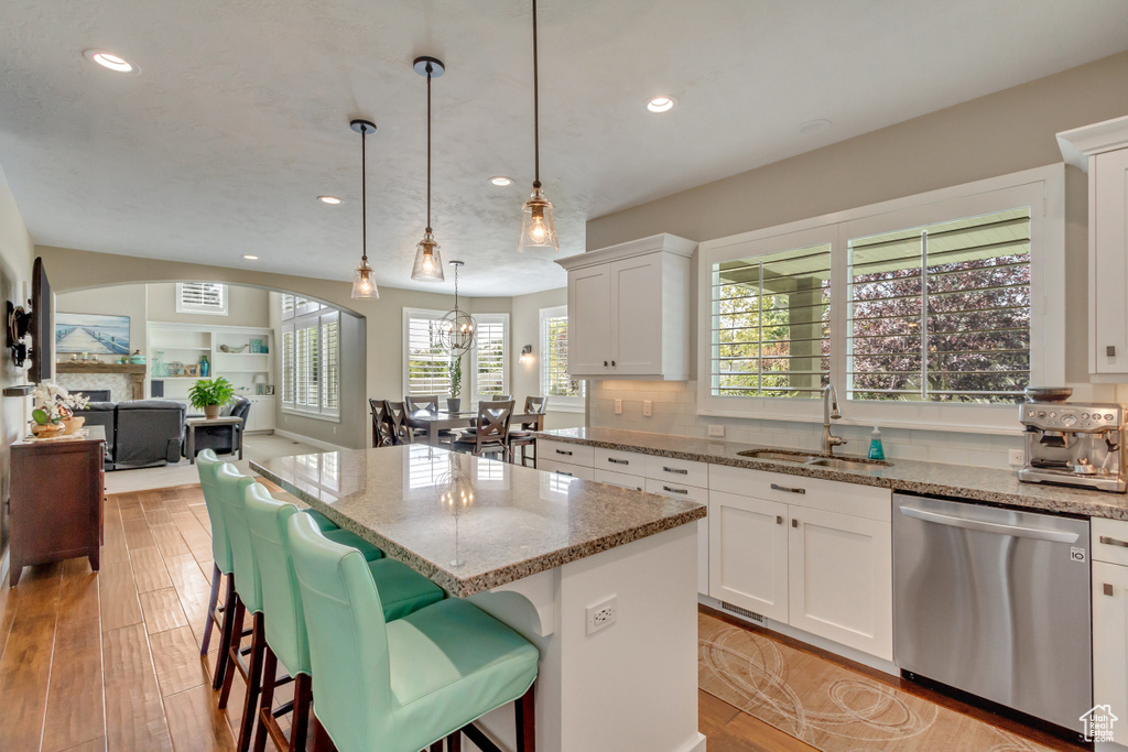 Kitchen featuring a wealth of natural light, stainless steel dishwasher, sink, and white cabinetry