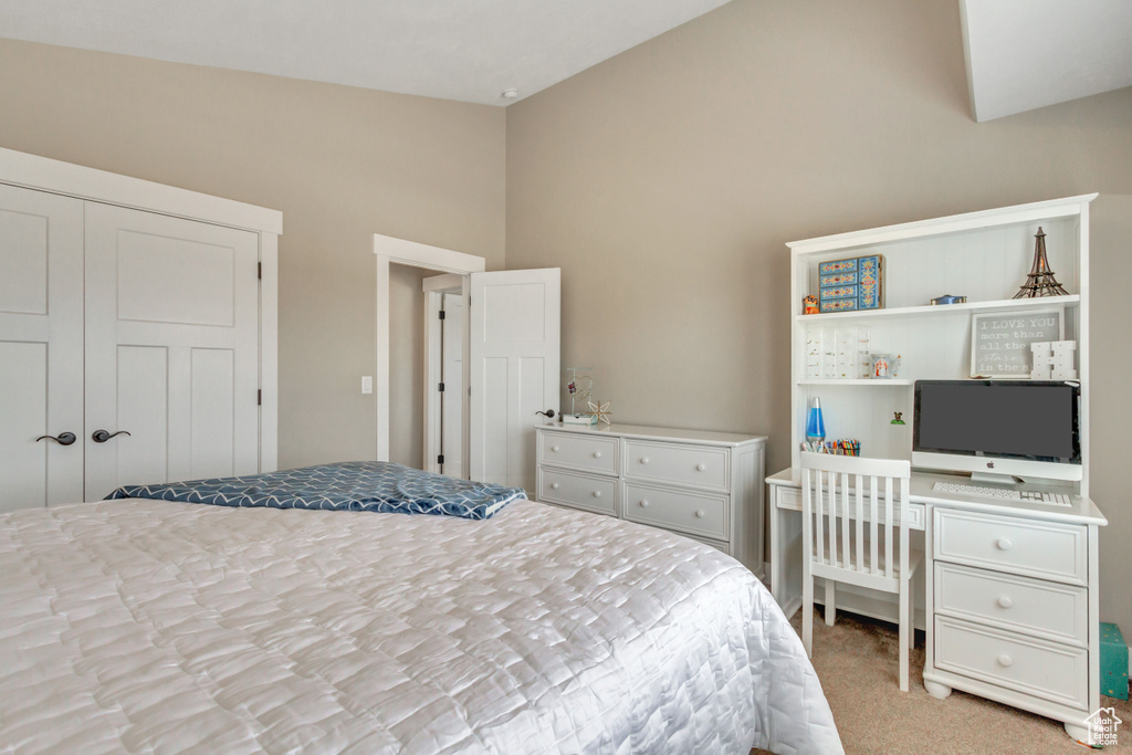 Bedroom with a closet, high vaulted ceiling, and light carpet