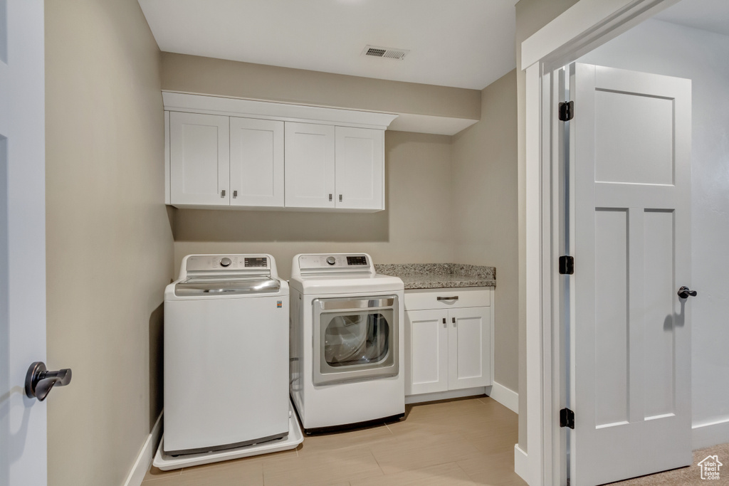 Washroom featuring cabinets and washer and dryer