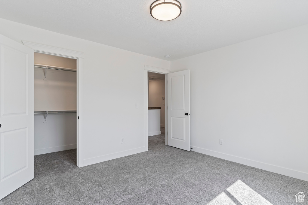 Unfurnished bedroom featuring carpet floors, a walk in closet, and a closet