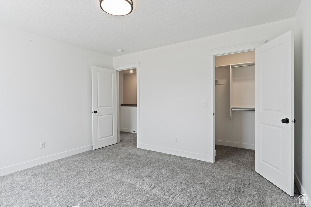 Unfurnished bedroom featuring a spacious closet, light colored carpet, and a closet