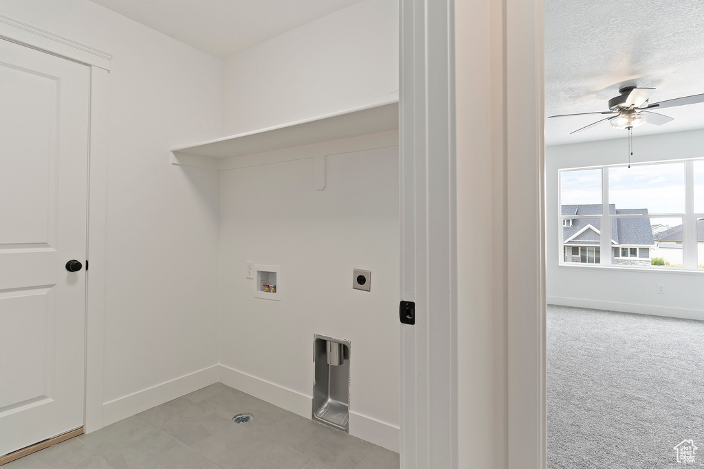 Clothes washing area featuring electric dryer hookup, a textured ceiling, washer hookup, ceiling fan, and light colored carpet