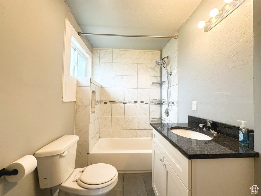 Full bathroom with tile patterned flooring, vanity, toilet, and tiled shower / bath combo