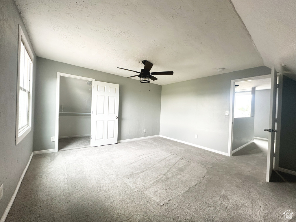 Unfurnished bedroom featuring vaulted ceiling, a textured ceiling, ceiling fan, and carpet flooring