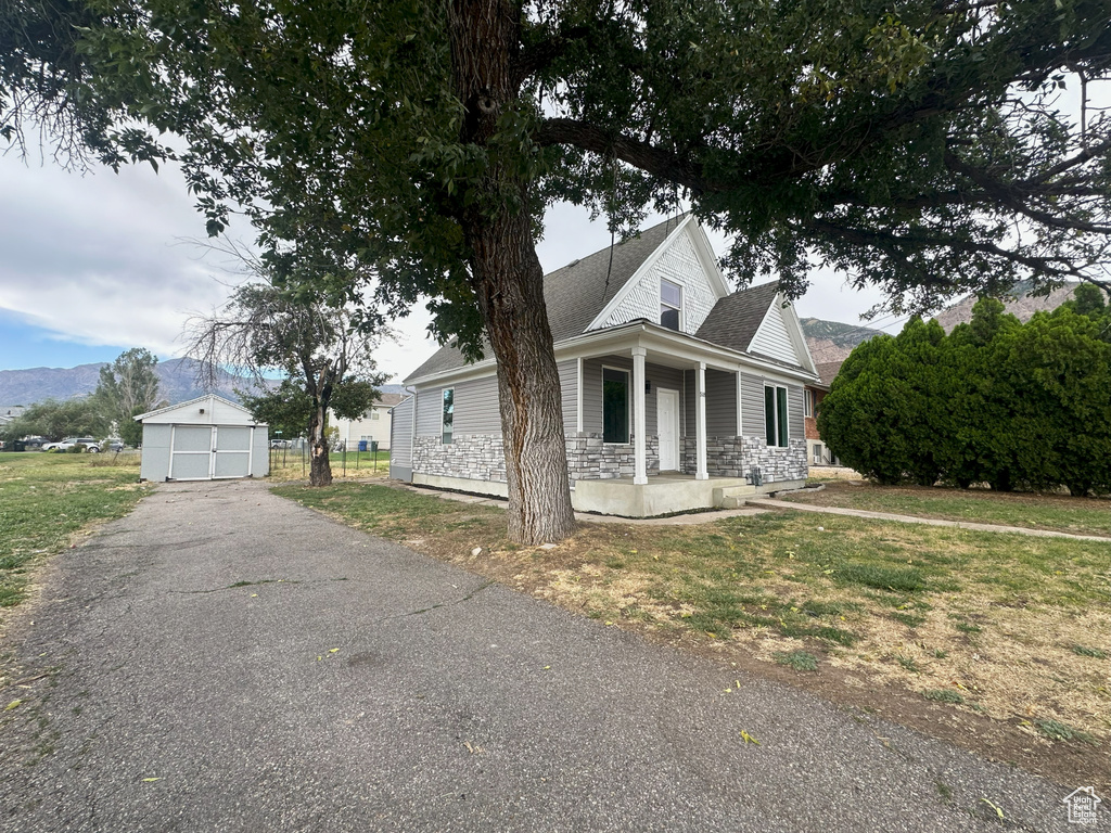 View of front of property with a porch, a garage, an outdoor structure, and a front yard