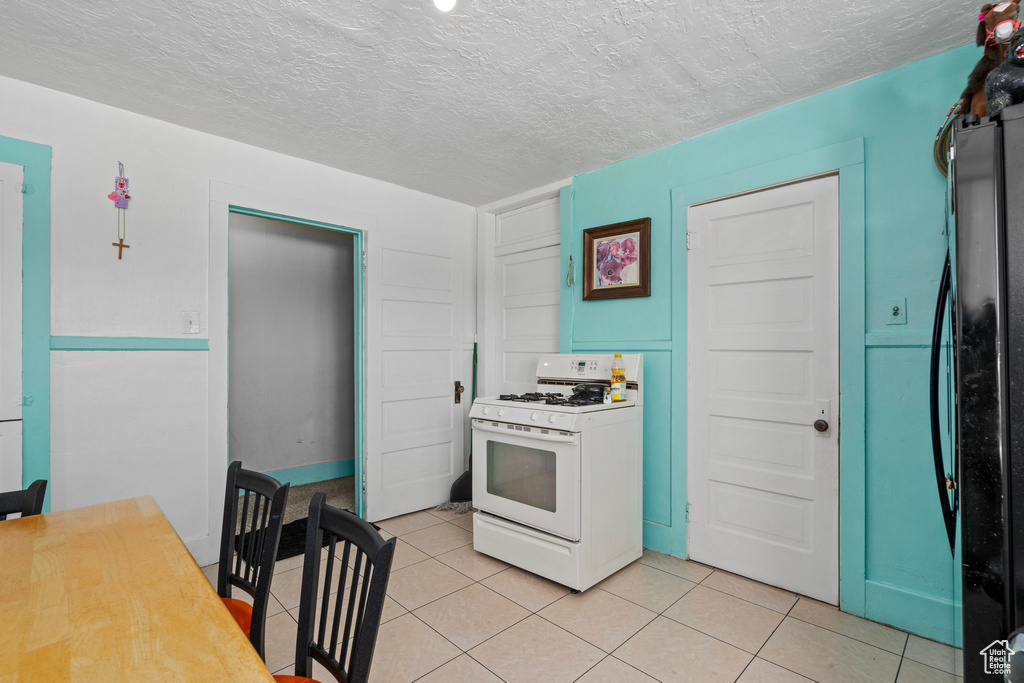 Kitchen featuring a textured ceiling, white range with gas cooktop, and light tile patterned flooring