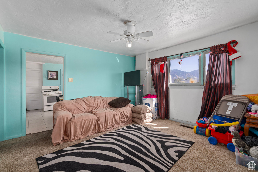 Bedroom with light colored carpet, ceiling fan, and a textured ceiling