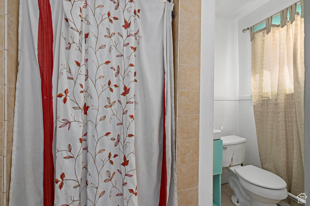 Bathroom featuring a shower with shower curtain, toilet, and tile patterned floors