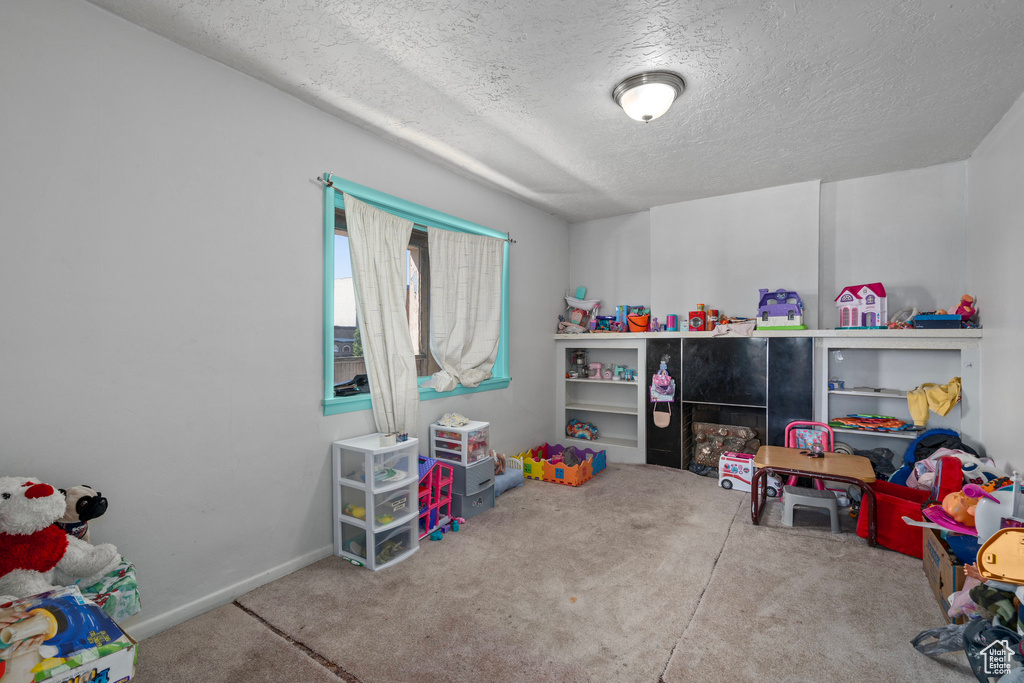 Playroom with a textured ceiling and carpet