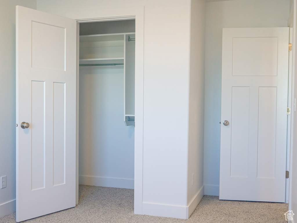 Unfurnished bedroom featuring a closet and light colored carpet