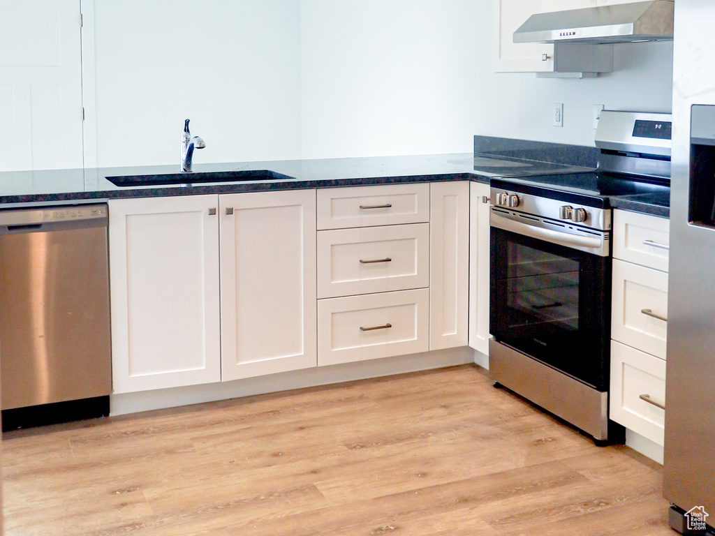 Kitchen with appliances with stainless steel finishes, sink, and white cabinets