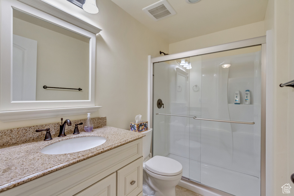 Bathroom with vanity, toilet, and a shower with shower door