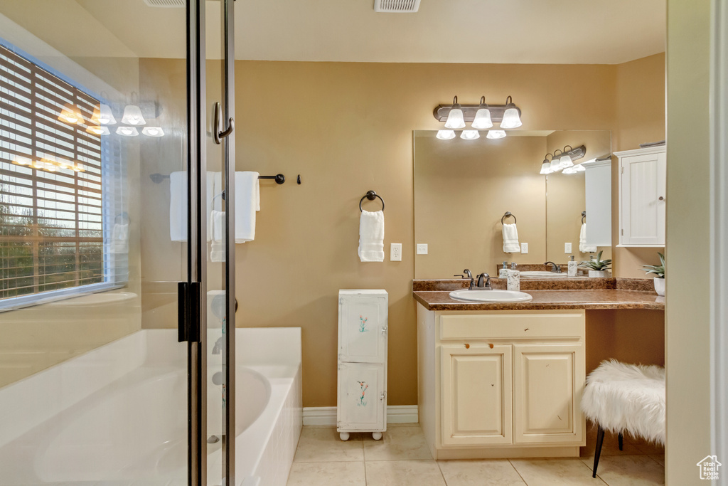 Bathroom with tile patterned flooring, a washtub, and vanity