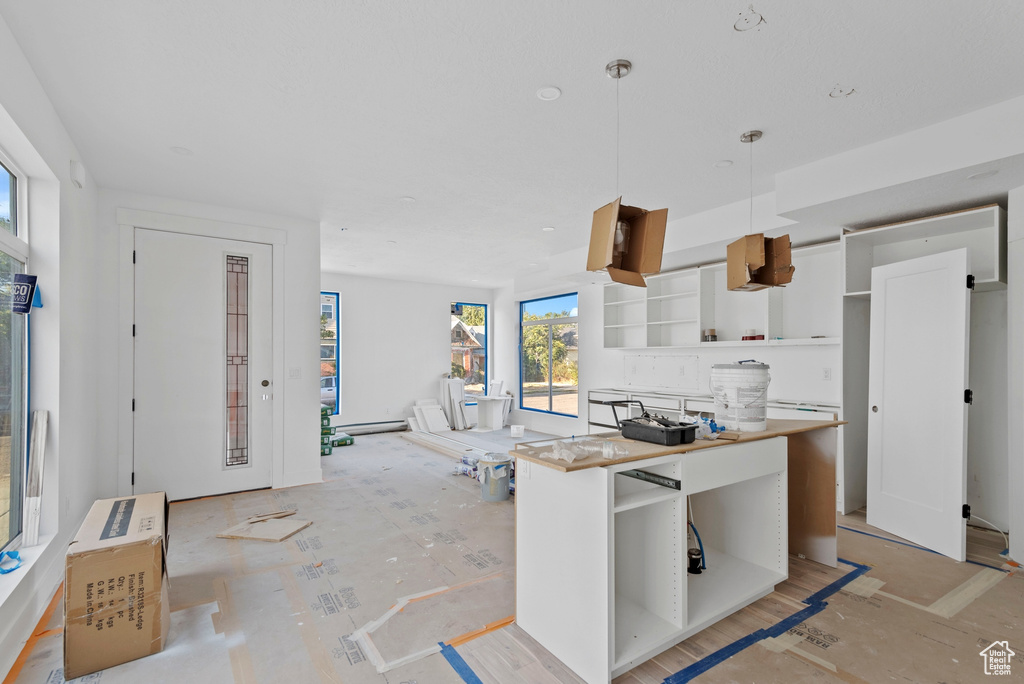 Kitchen with a baseboard heating unit, pendant lighting, and white cabinets