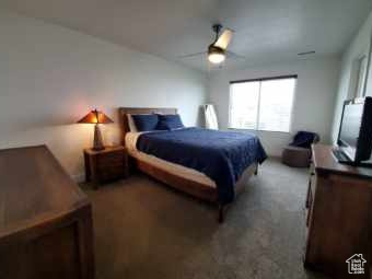 Carpeted bedroom with a ceiling fan