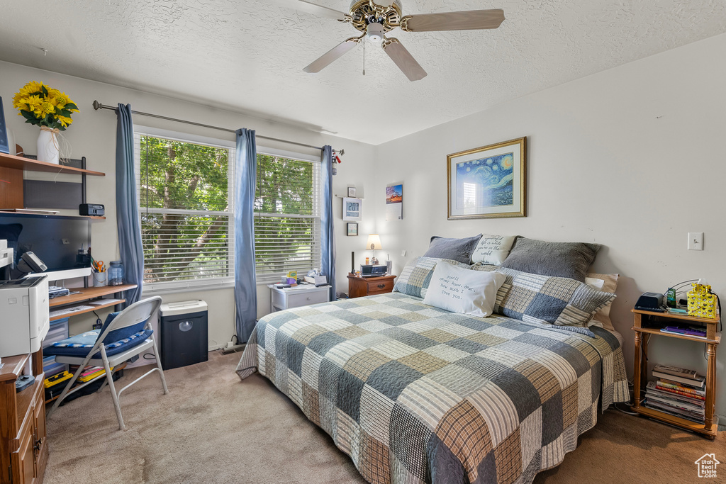 Carpeted bedroom featuring ceiling fan and a textured ceiling