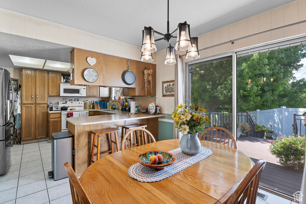 Tiled dining space featuring a textured ceiling, a notable chandelier, and sink