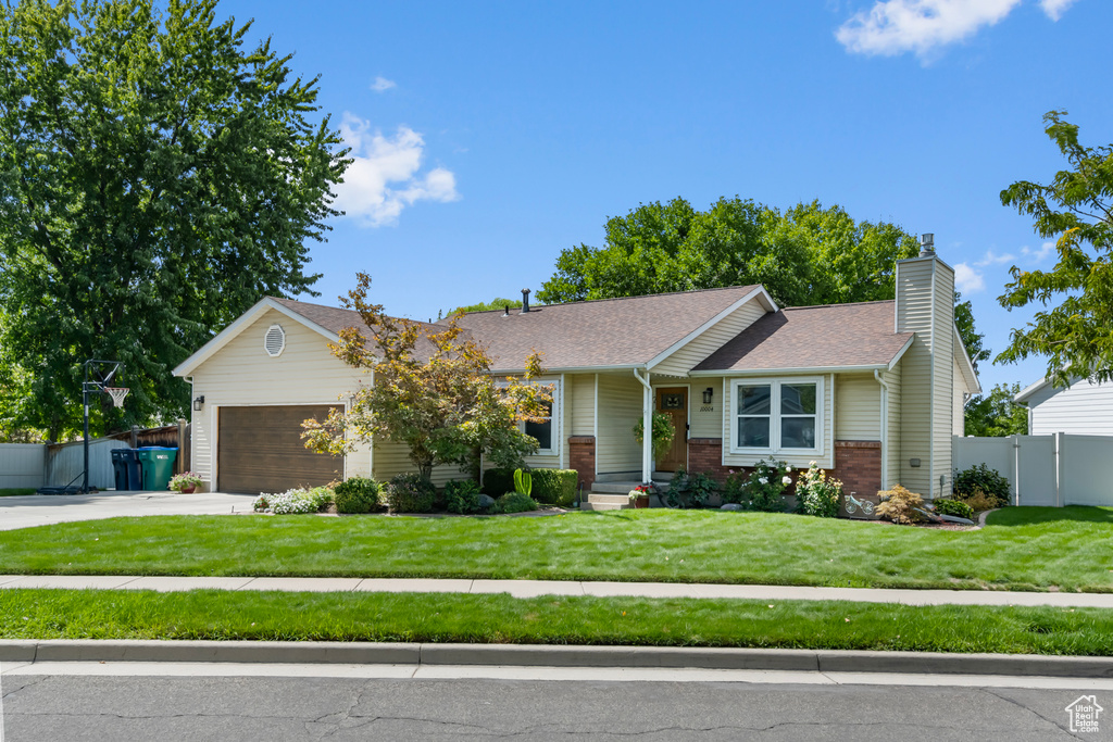 View of front facade featuring a garage and a front lawn