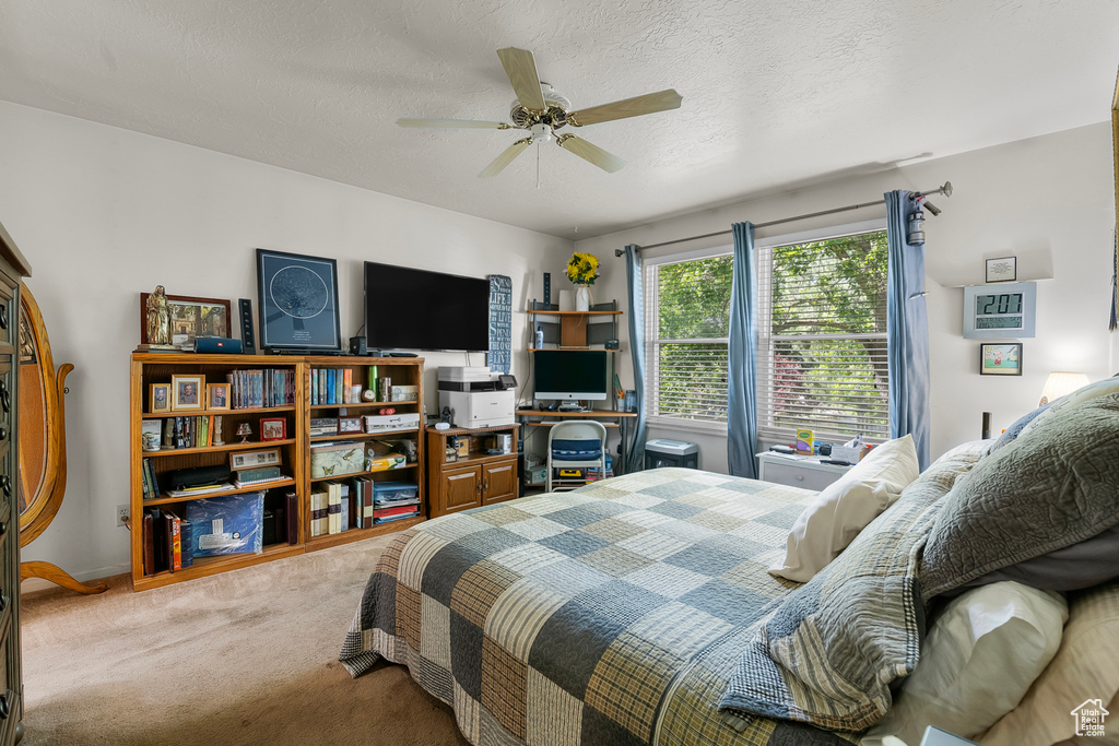 Carpeted bedroom featuring ceiling fan and a textured ceiling