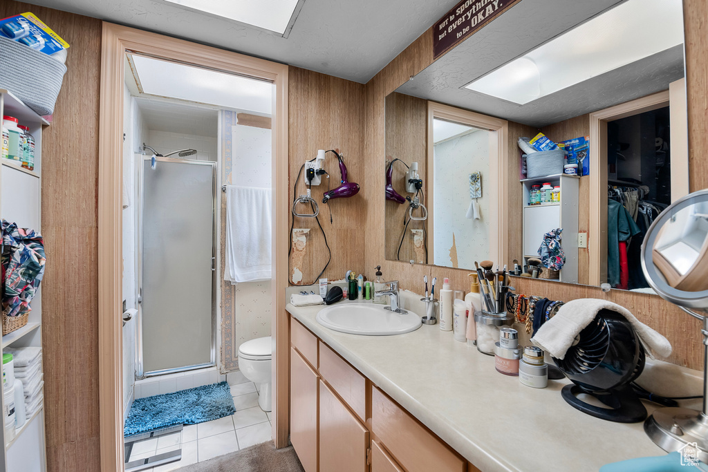 Bathroom with tile patterned flooring, walk in shower, toilet, and vanity