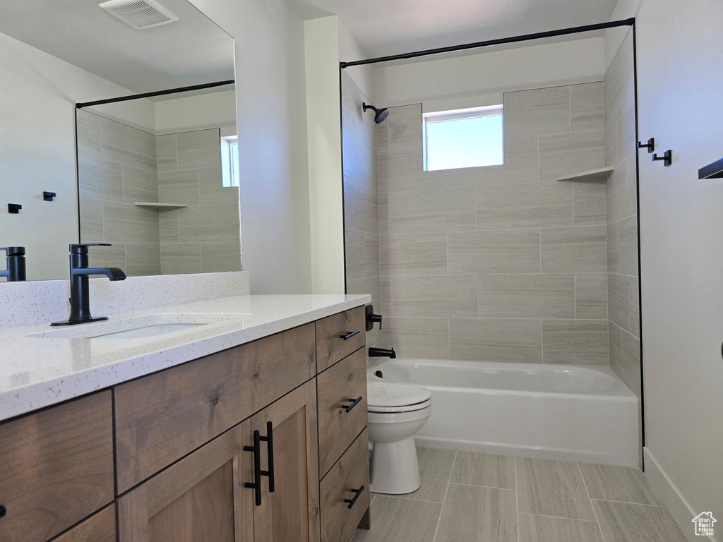 Full bathroom featuring vanity, toilet, and tiled shower / bath combo