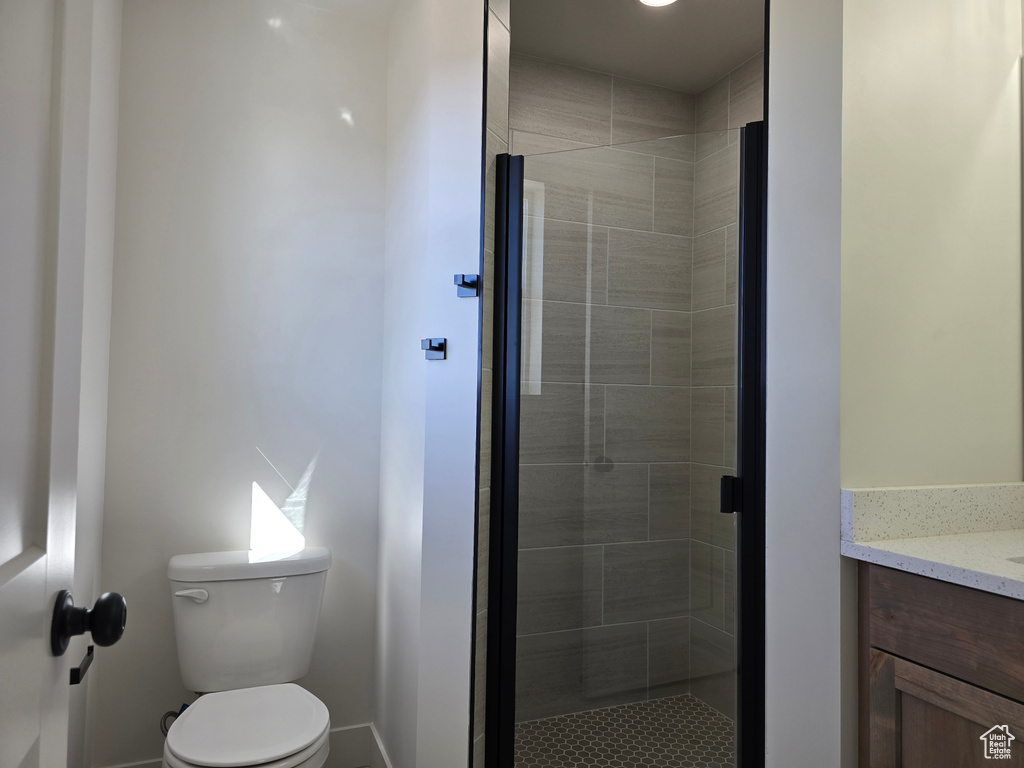 Bathroom with toilet, an enclosed shower, and vanity