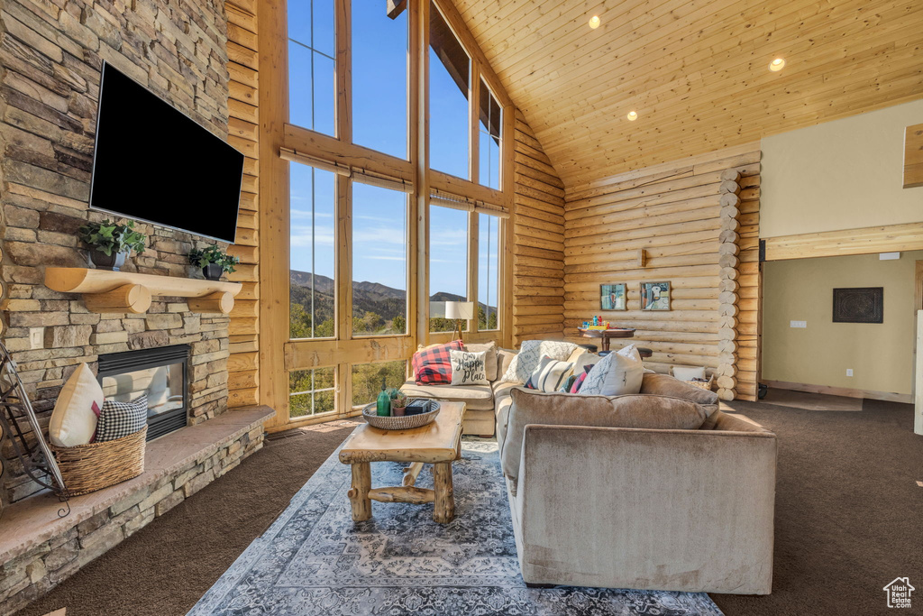 Carpeted living room with wood ceiling, rustic walls, a stone fireplace, and high vaulted ceiling