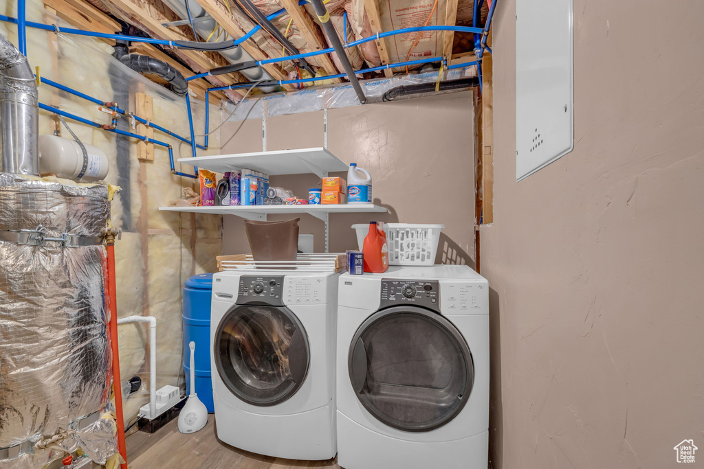 Clothes washing area with independent washer and dryer and light hardwood / wood-style floors