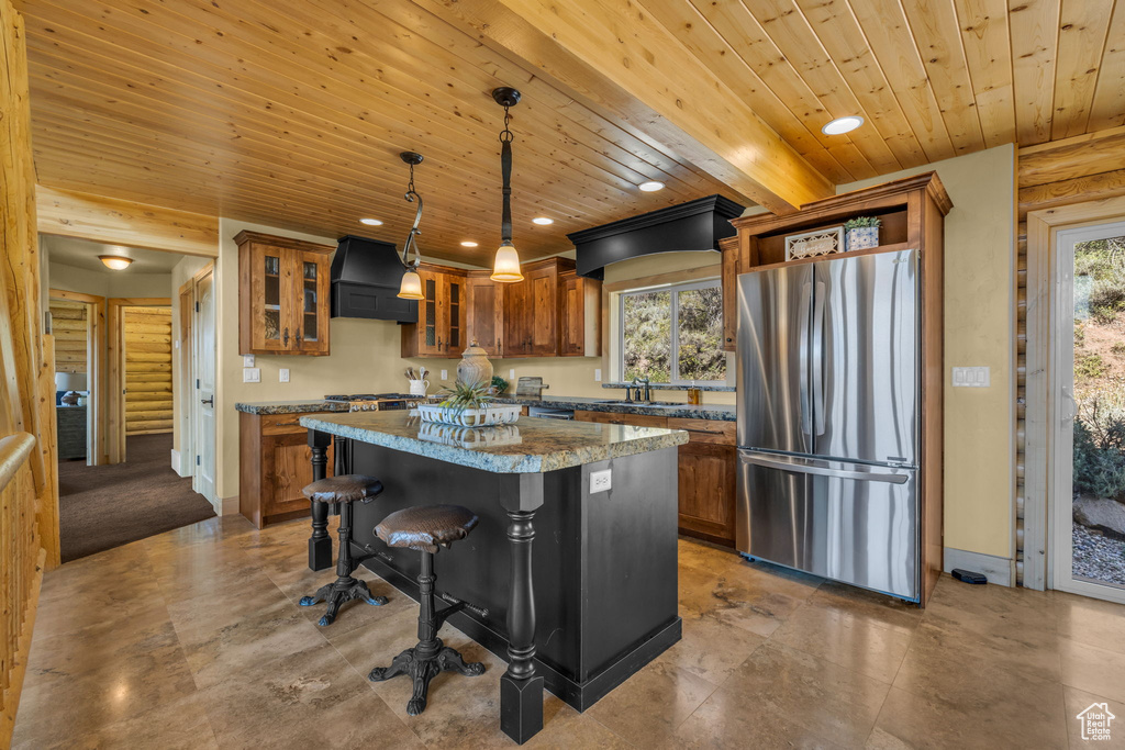 Kitchen with plenty of natural light, a center island, stainless steel fridge, and premium range hood