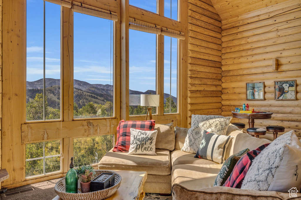 Living room featuring a mountain view, a healthy amount of sunlight, and rustic walls