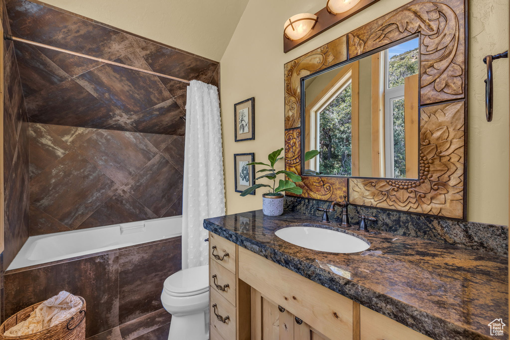 Full bathroom with shower / bath combo, vaulted ceiling, toilet, and vanity