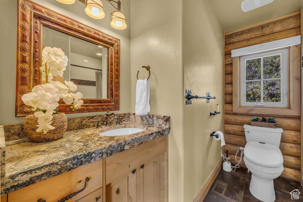 Bathroom with vanity, toilet, a shower with shower curtain, and rustic walls