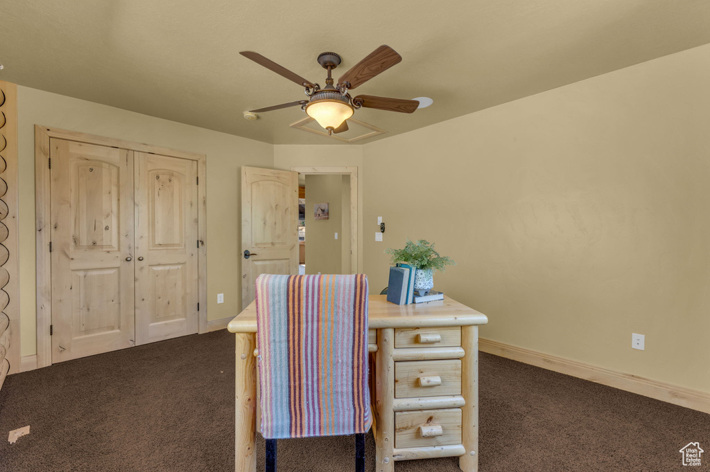 Unfurnished office with ceiling fan and dark colored carpet